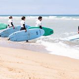 Surfer/-innen auf dem Weg ins Wasser